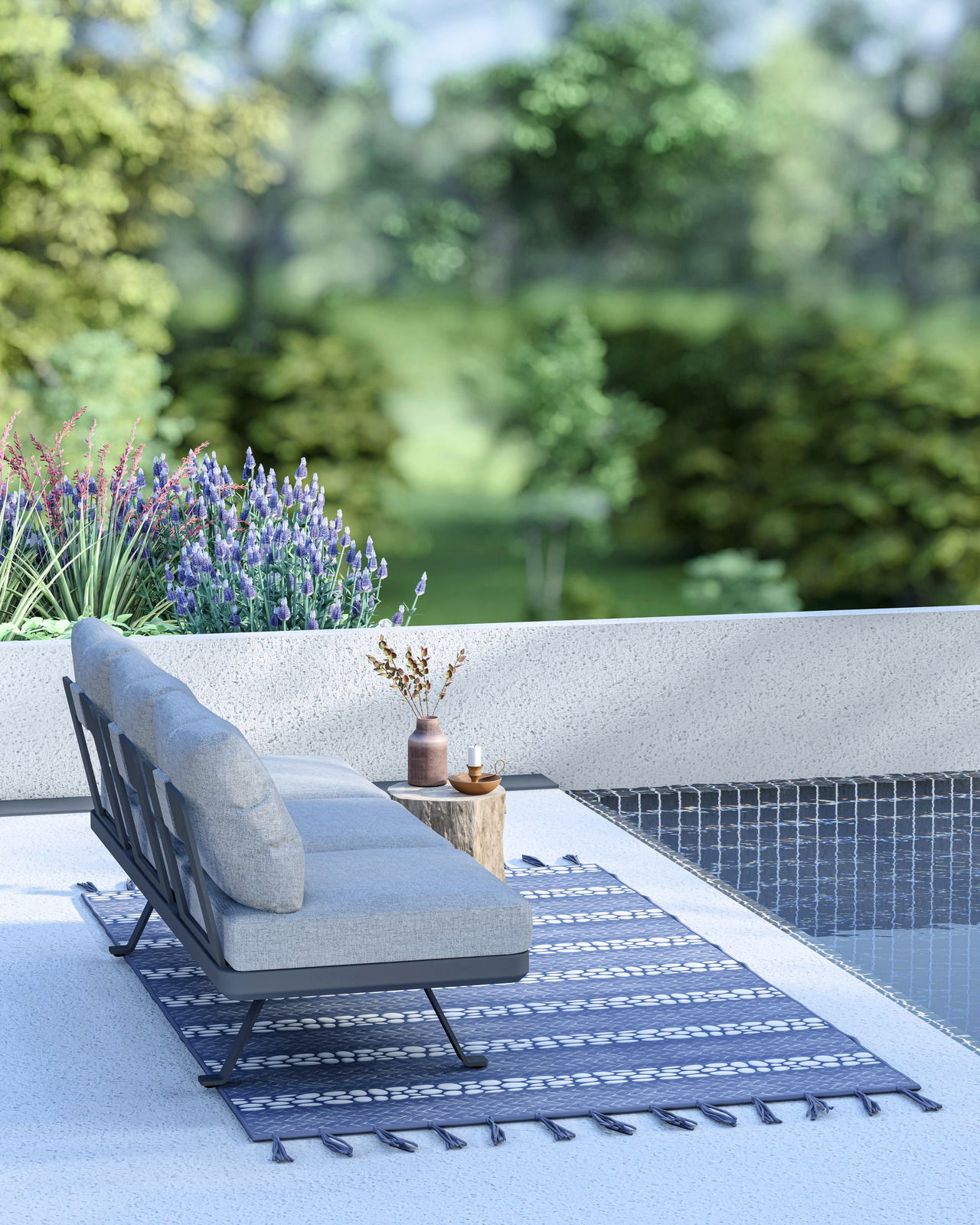 Seitliche Perspektive auf ein modernes 3-Sitzer Loungeelement mit grauen Kissen, platziert auf einer Terrasse neben einem Pool, umgeben von grüner Natur und Blumen.