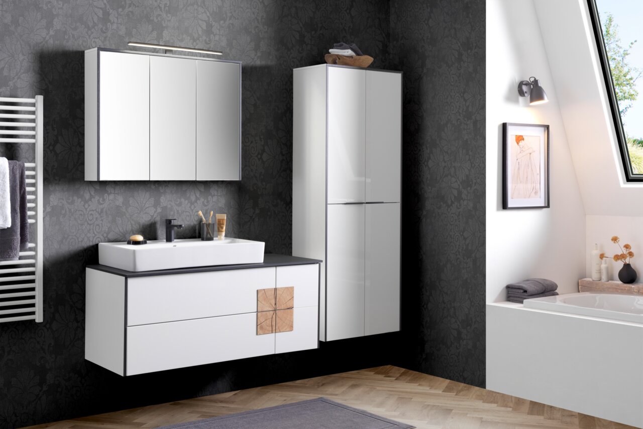 Modernes Waschtisch-Set in einem stilvollen Badezimmer mit dunkler Tapete, bestehend aus einem weißen Waschtisch mit Spiegel und einem hohen Schrank, seitliche Perspektive.