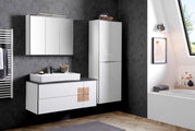 Modernes Waschtisch-Set in einem stilvollen Badezimmer mit dunkler Tapete, bestehend aus einem weißen Waschtisch mit Spiegel und einem hohen Schrank, seitliche Perspektive.