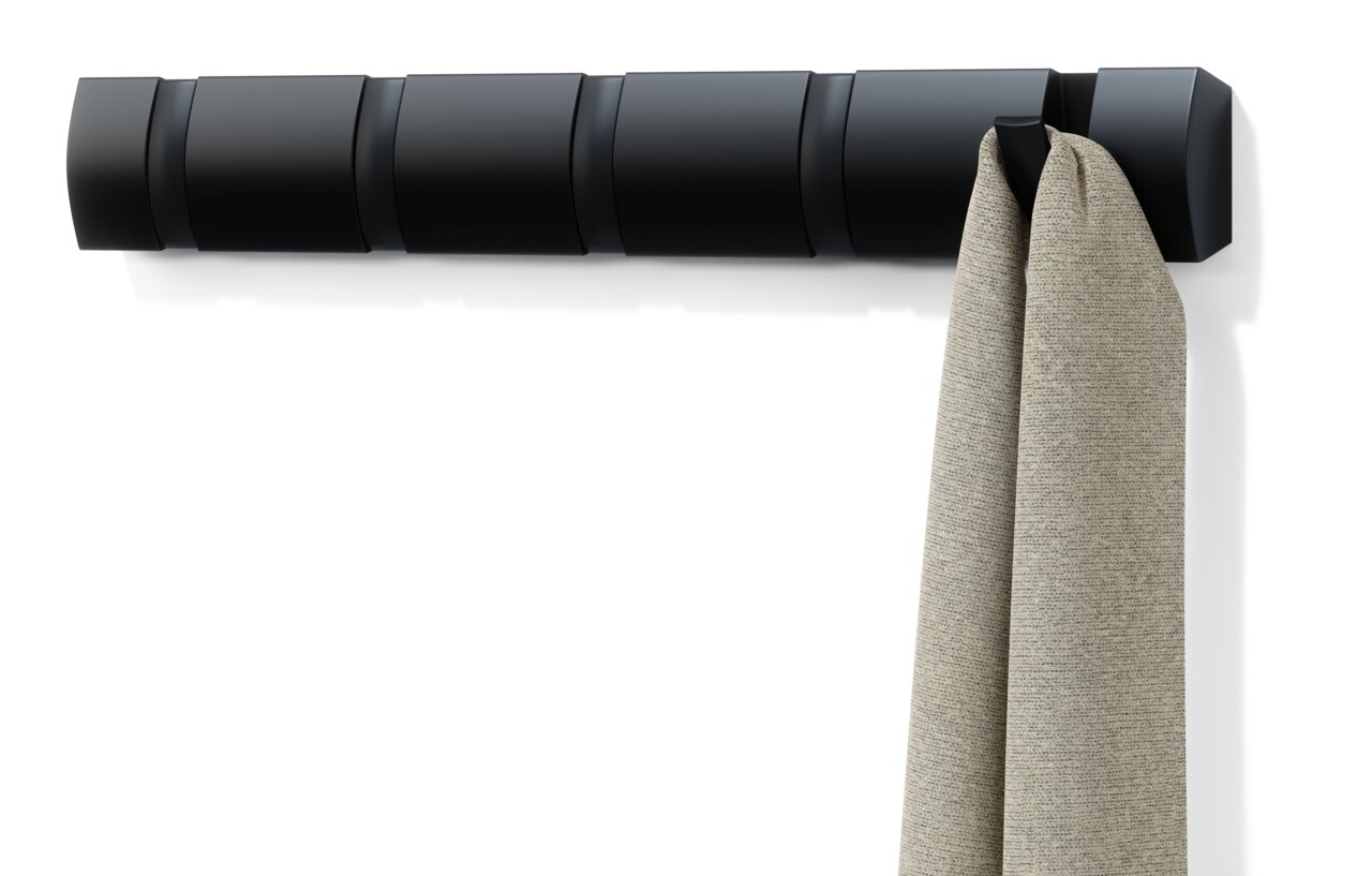Schwarze Wandgarderobe Umbra FLIP mit mehreren Haken, an der ein beiger Stoff hängt, seitliche Perspektive.