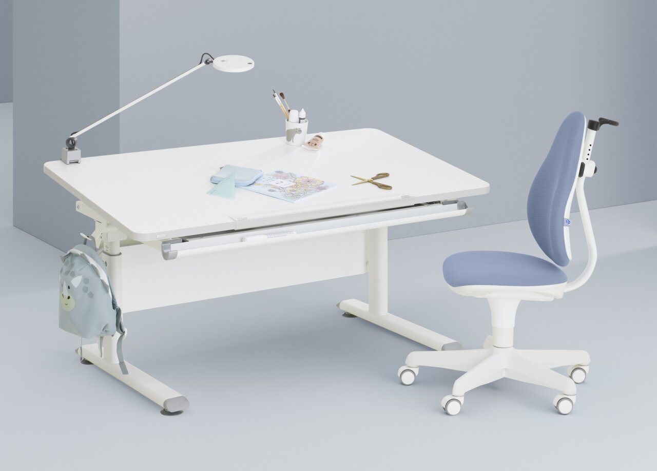 Moderne draaistoel voor jongeren in blauw en wit, gezien vanaf de zijkant, naast een wit bureau met een lamp en schrijfbenodigdheden.