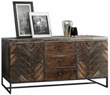 Rustikales Sideboard aus Holz mit Fischgrätenmuster, drei Schubladen und zwei Türen, dekoriert mit zwei gerahmten Schwarz-Weiß-Fotos und zwei Vasen, Perspektive von vorne.