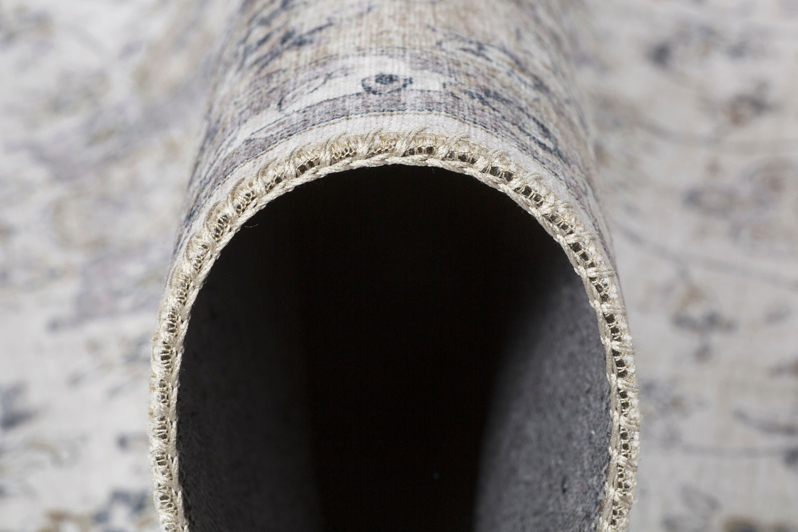 Nahaufnahme eines zusammengerollten Teppichs mit sichtbarer Kante und Textur, Perspektive von der Seite