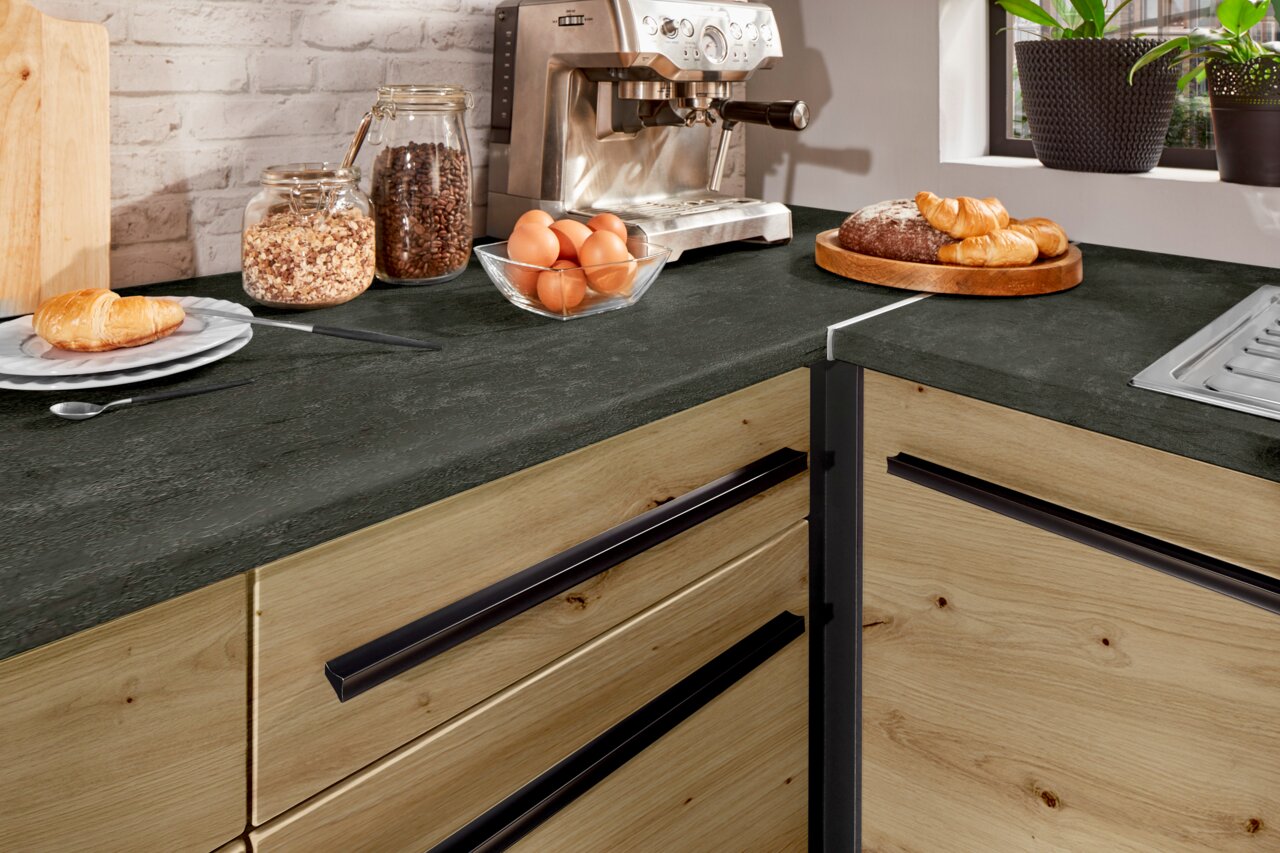 Hoekonderkast in een moderne keuken met een donker werkblad, houten fronten en zwarte handgrepen, gezien vanuit bovenaf.