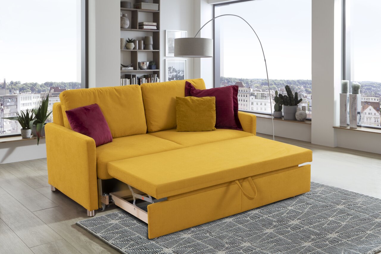 Gelbes Funktionssofa mit ausgezogenem Bettmechanismus, dekoriert mit roten und gelben Kissen, in einem modernen Wohnzimmer mit Stadtblick, seitliche Perspektive.