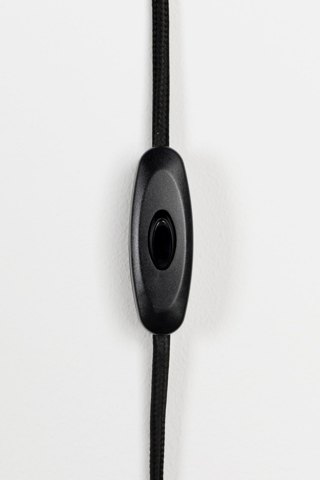 Nahaufnahme eines schwarzen Kabelschalters an einem schwarzen Kabel, vertikale Perspektive