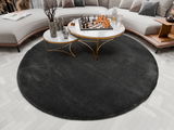 Runder, dunkelgrauer Hochflor-Teppich in einem modernen Wohnzimmer, von oben betrachtet, mit einem eleganten Couchtisch und einer stilvollen Couch.