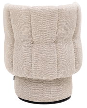 Achterkant van een beige fauteuil met patroon en een ronde voet.