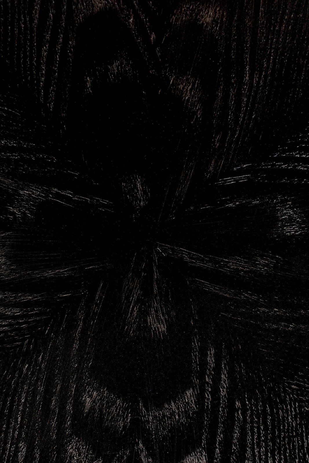 Nahaufnahme der dunklen Holzmaserung eines Esstisches aus der Vogelperspektive.