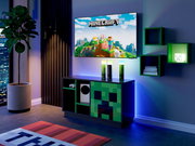 Minecraft Gaming-Setup im Wohnzimmer: Wand-TV mit Minecraft-Motiv über einem Sideboard mit Creeper-Front und LED-Beleuchtung, aufgenommen in schräger Frontansicht von links.