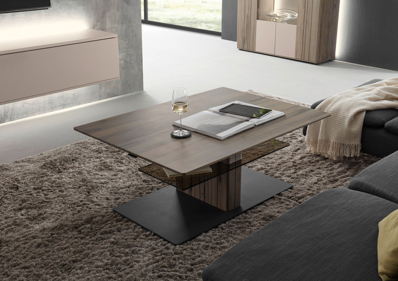 Moderner Couchtisch aus Holz mit Glasablage, seitliche Perspektive, dekoriert mit einem Weinglas und einem Buch auf einem Teppichboden.