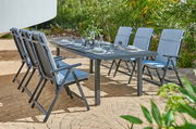 Sechs blaue Klappsessel um einen gedeckten Gartentisch auf einer Terrasse, seitliche Perspektive
