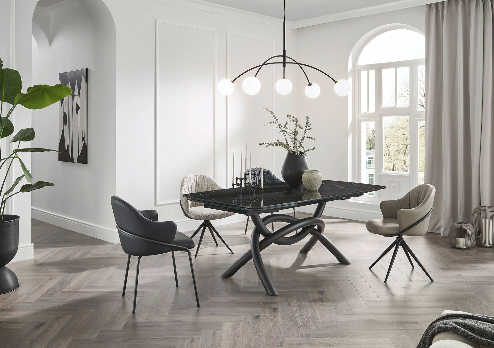 Emilio Belluti Esstisch MATTEO Moderner Essbereich mit einem schwarzen Esstisch und eleganten Armlehnstühlen, aus der Perspektive von schräg vorne aufgenommen.