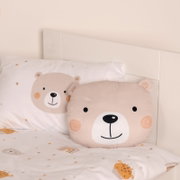Een beige kussen in de vorm van een beer op een bed, van voren gefotografeerd, met bijpassend beddengoed met een beerprint.