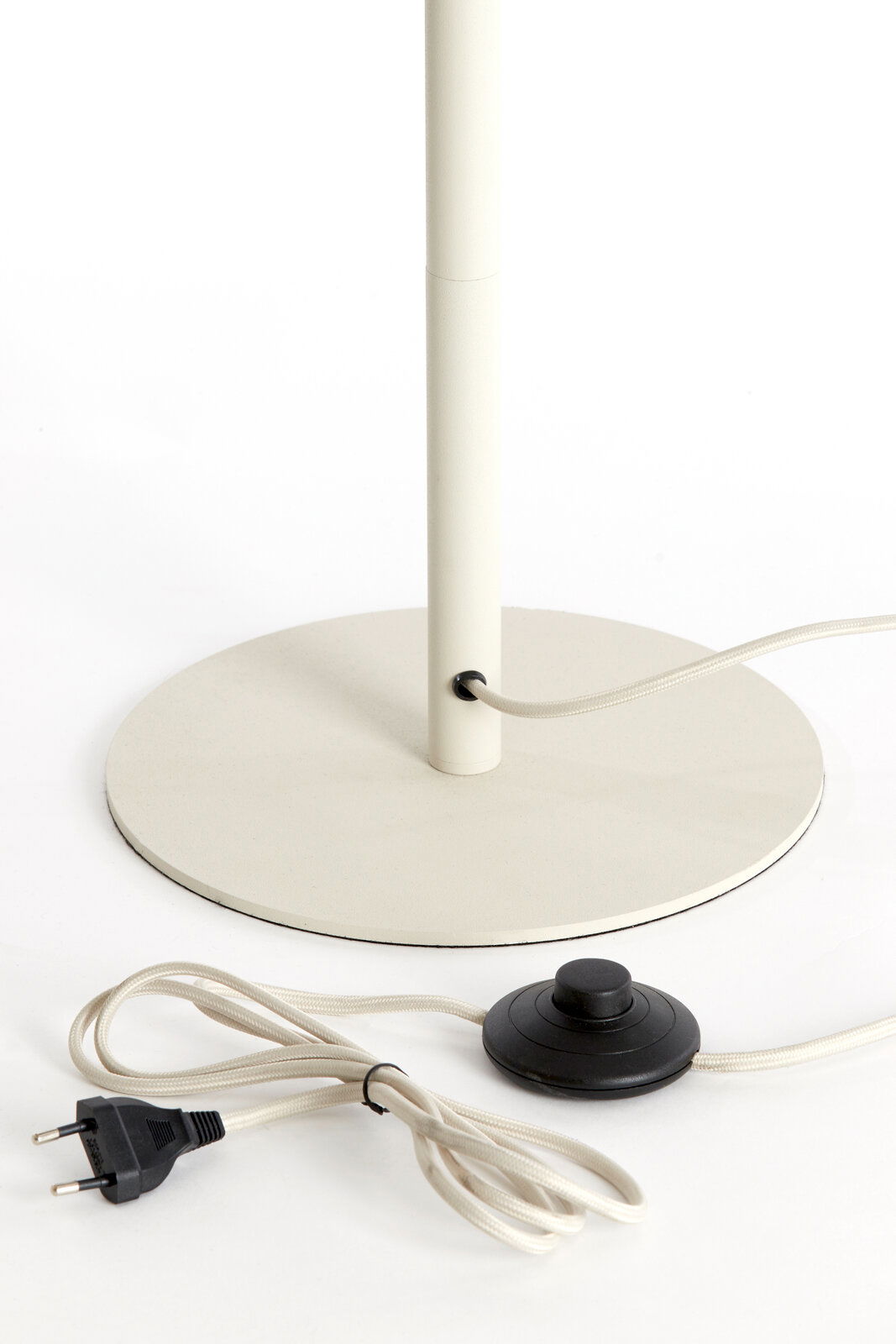 Nahaufnahme einer Stehleuchte mit rundem Sockel, Kabel und Fußschalter.