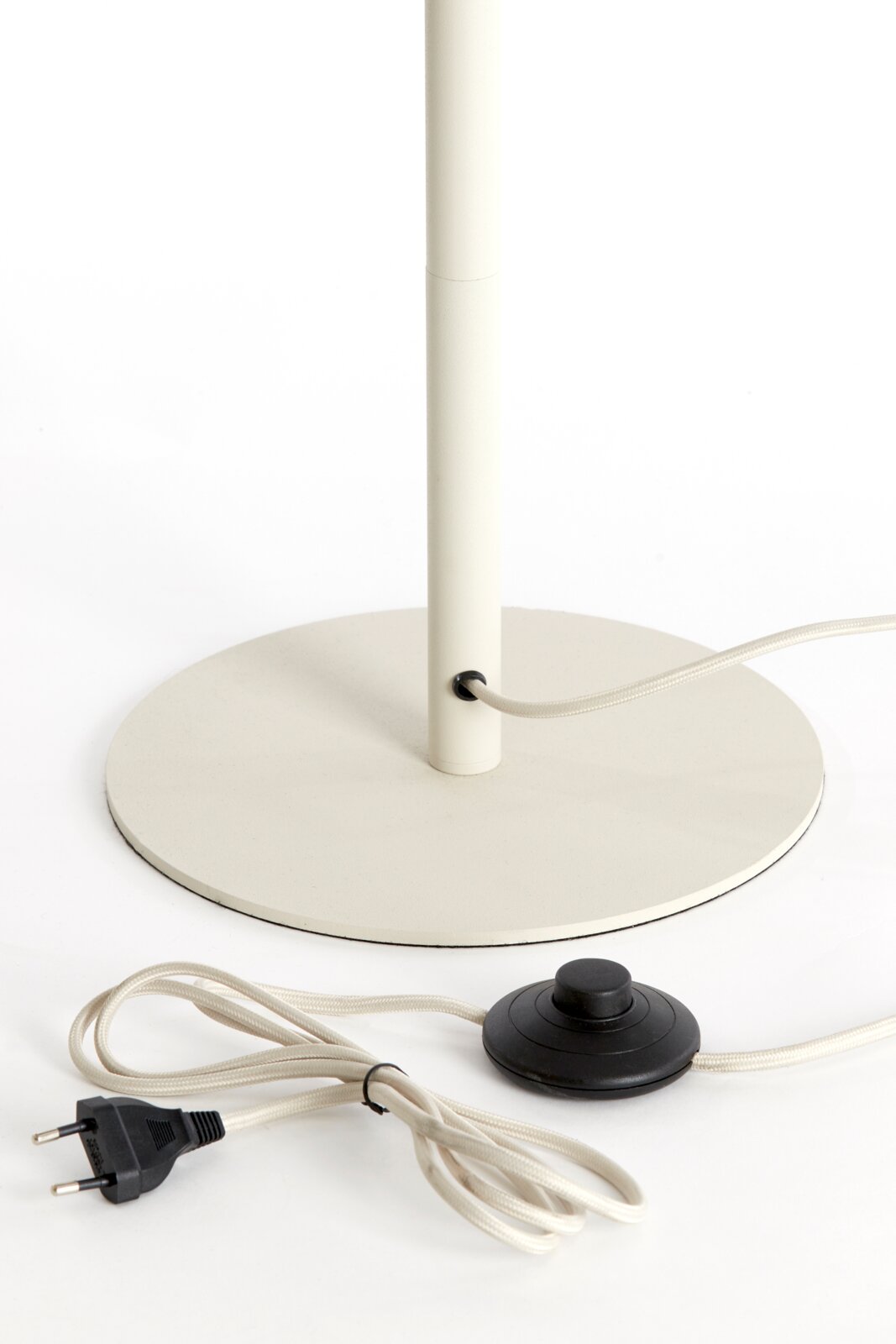 Close-up van een staande lamp met ronde voet, snoer en voetschakelaar.