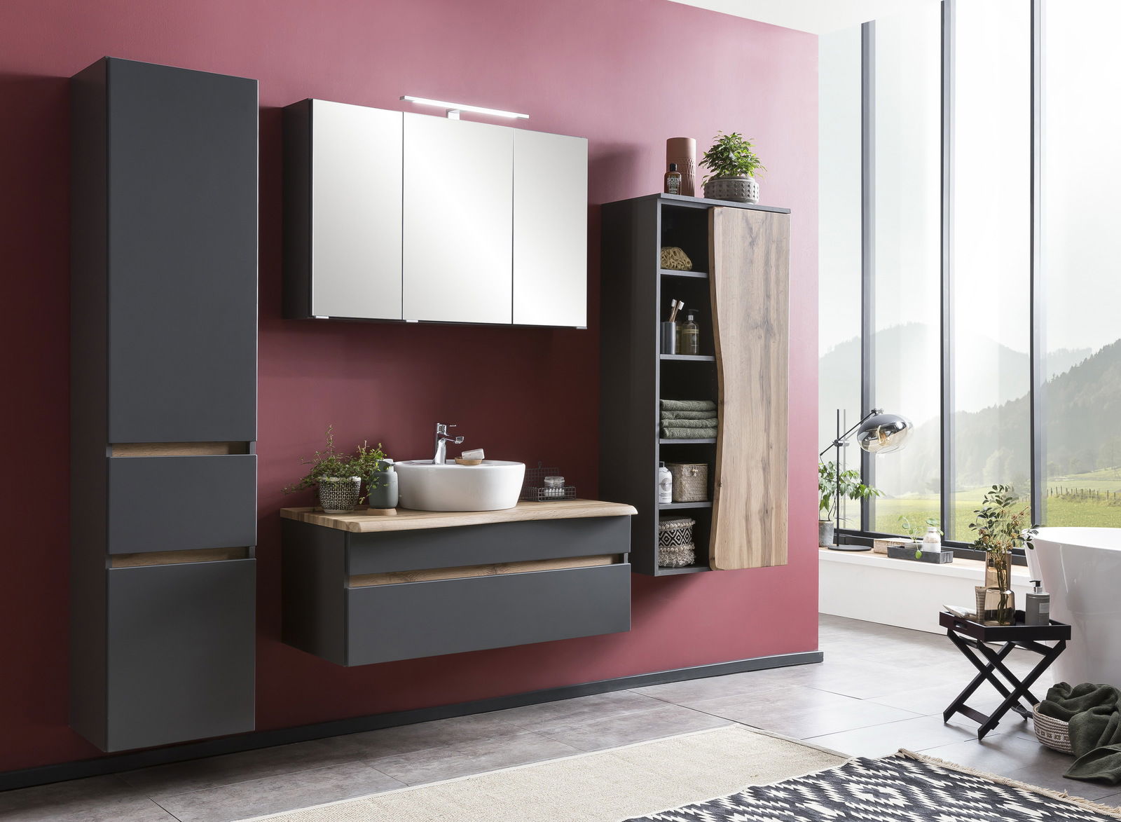 Moderner Spiegelschrank in einem stilvollen Badezimmer mit roter Wand und großen Fenstern, seitliche Perspektive.