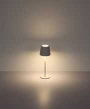 Moderne Tischleuchte mit schlichtem Design, frontal abgebildet, strahlt warmes Licht aus.