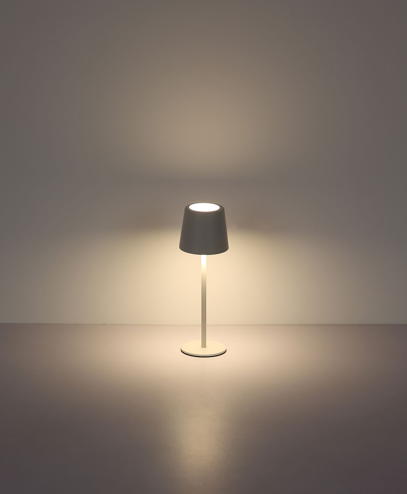 Moderne Tischleuchte mit schlichtem Design, frontal abgebildet, strahlt warmes Licht aus.