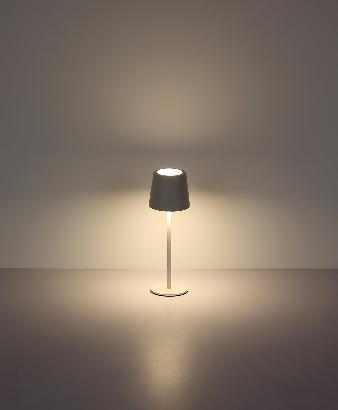 Moderne Tischleuchte mit schlichtem Design, frontal abgebildet, strahlt warmes Licht aus.