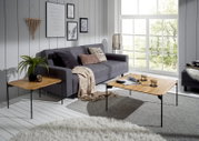 Moderner Couchtisch mit Holzplatte und schwarzen Metallbeinen in einem stilvollen Wohnzimmer, seitliche Perspektive.