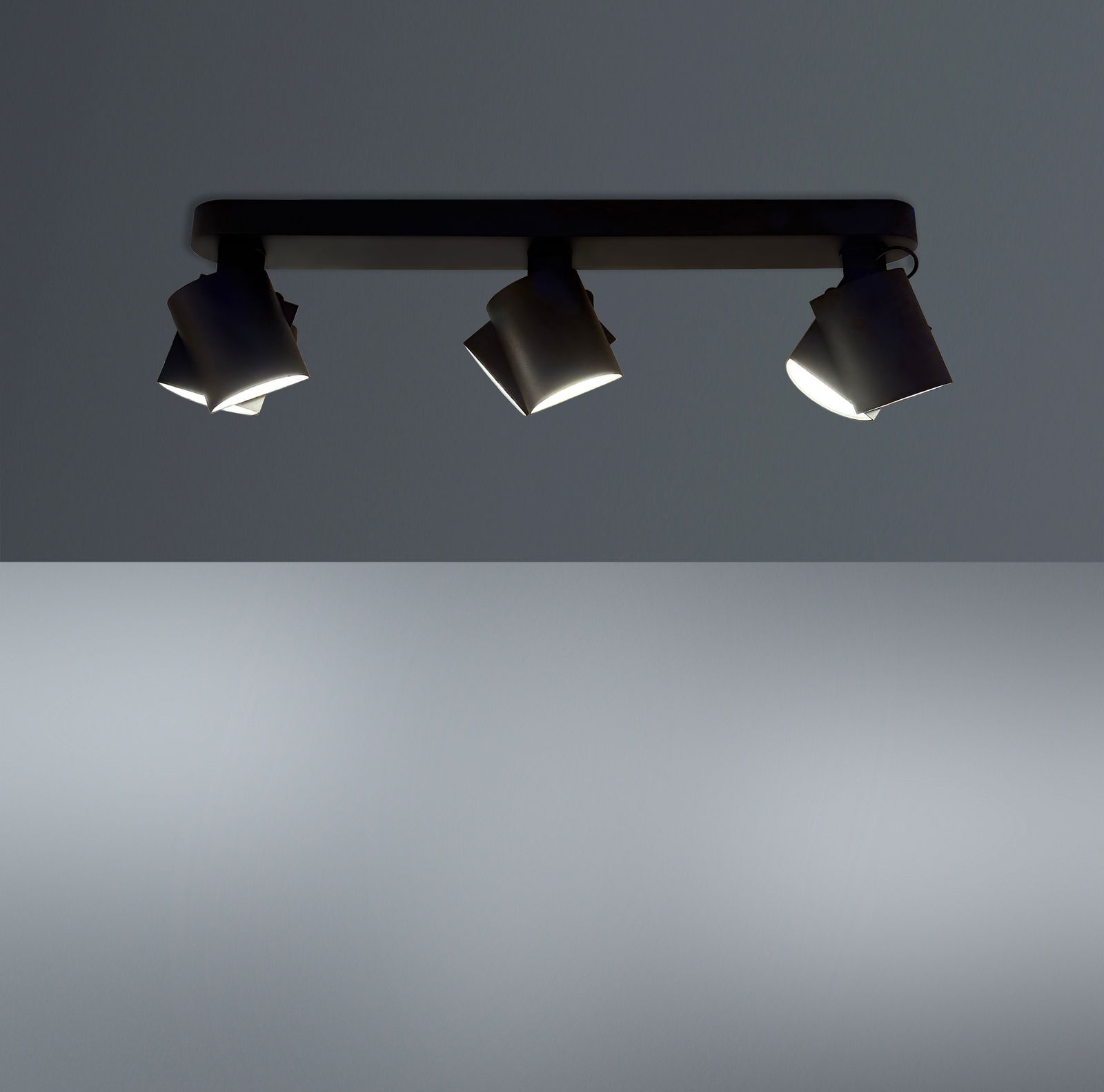Dreifacher LED-Spot von unten betrachtet, montiert an einer Deckenleiste, mit modernem Design und verstellbaren Leuchten.