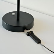 Schwarze Akku-Tischleuchte mit rundem Sockel und USB-Anschluss, seitliche Perspektive.