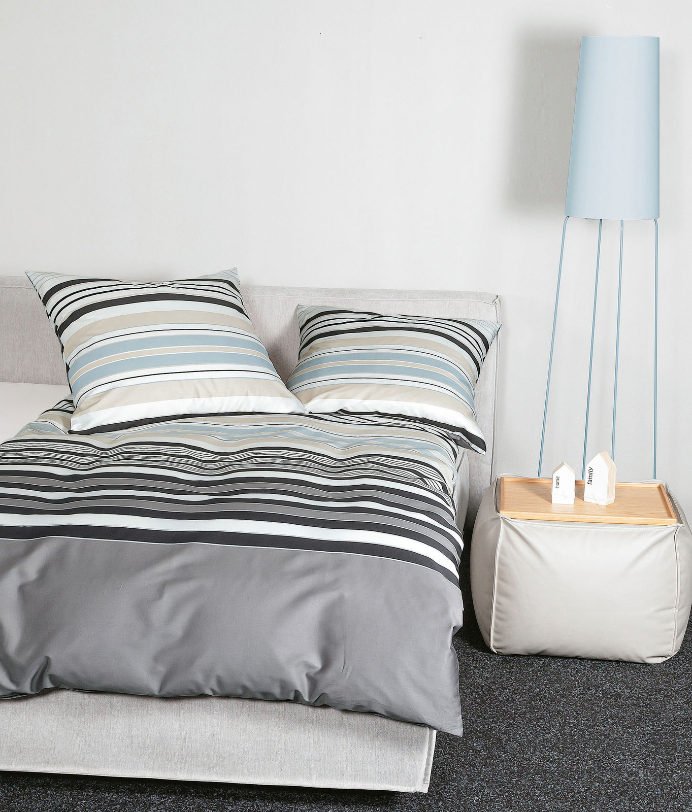 Bettwäsche-Set mit Streifenmuster in Blau, Grau und Weiß auf einem Bett, seitliche Perspektive