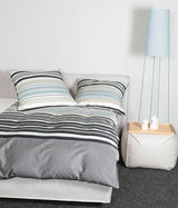 Bettwäsche-Set mit Streifenmuster in Blau, Grau und Weiß auf einem Bett, seitliche Perspektive
