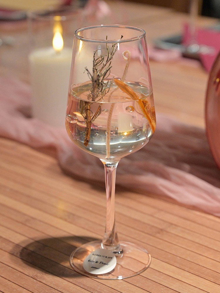 Elegante transparante kaars in een wijnglas in gin-tonicstijl, afgewerkt met botanische decoratie.