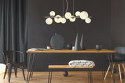 Moderne Hängeleuchte mit mehreren runden, weißen Glaskugeln, die von einer Metallstange hängen, in einem stilvoll eingerichteten Raum mit Holztisch und schwarzen Dekorationselementen. Perspektive: Frontalansicht.