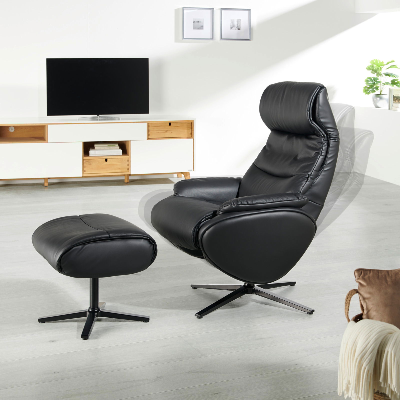 Schwarzer Relaxsessel mit Hocker in einem modernen Wohnzimmer, seitliche Perspektive