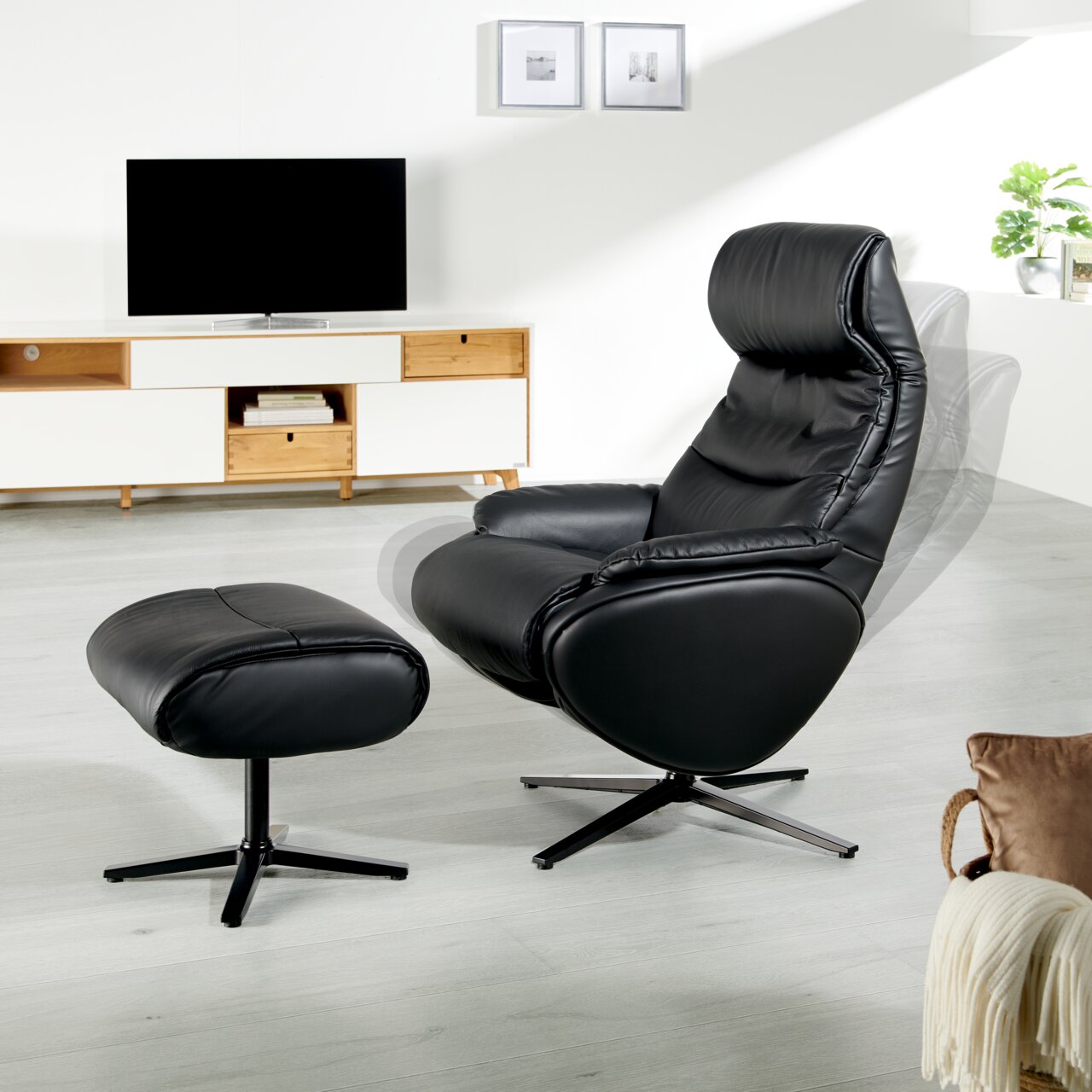 Zwarte relaxfauteuil met voetenbank in een moderne woonkamer, zijaanzicht