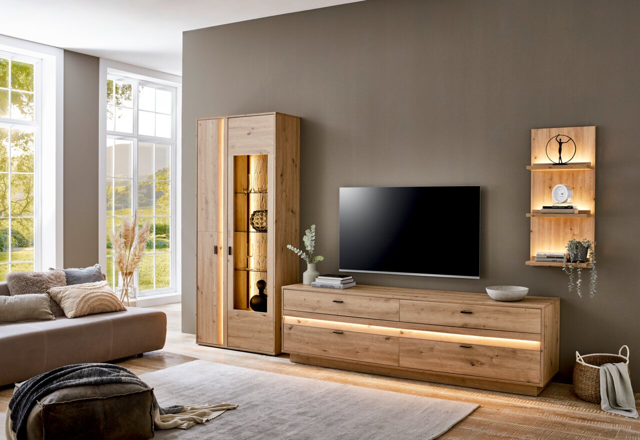 Moderne Wohnzimmer-Wandkombination aus Holz mit TV-Schrank, Vitrine und beleuchtetem Wandregal, seitliche Perspektive