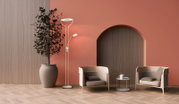 Moderne Stehlampe in Weiß mit ringförmigem Hauptlicht und kleinem Lesearm neben großem Pflanzkübel, zwei Loungesesseln und Beistelltisch vor terrakottafarbener Wand mit Rundbogen; Perspektive: frontale Ansicht auf Augenhöhe.