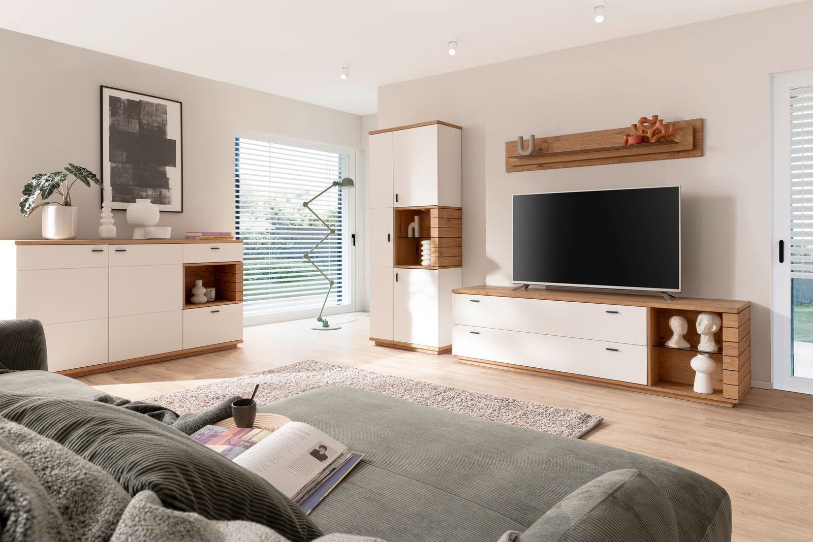 Modernes Wohnzimmer mit einem Highboard in Holz- und Weißtönen, seitliche Perspektive. Das Highboard ist Teil einer stilvollen Wohnwand mit integriertem Fernseher und dekorativen Elementen.