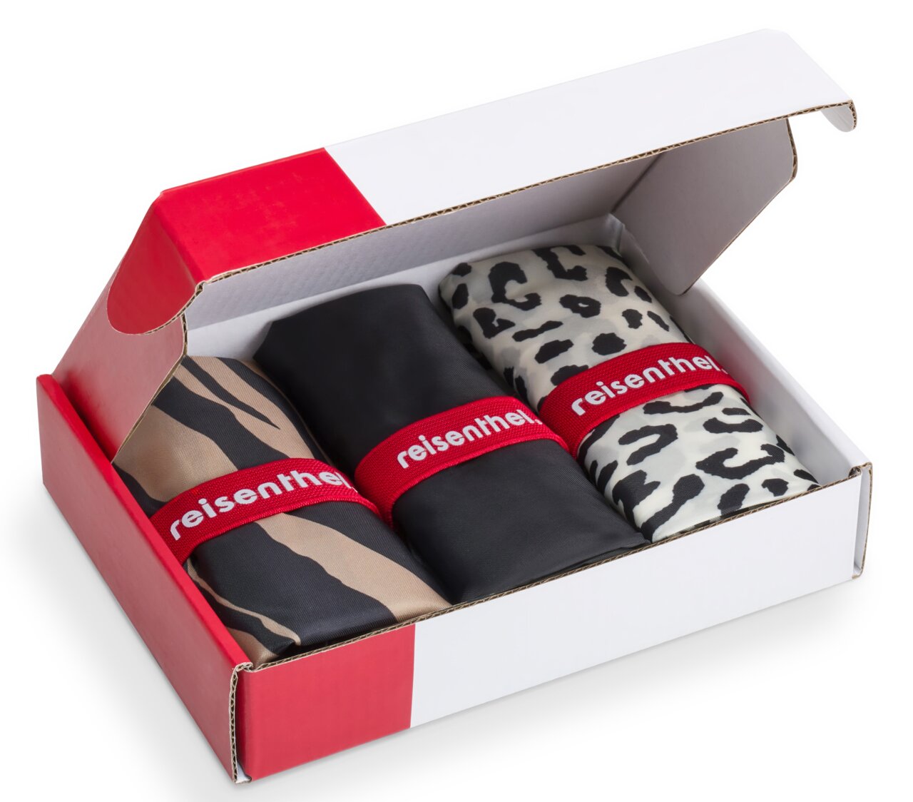 Drie opgevouwen mini-maxi-shoppers in een open witte en rode doos, met verschillende patronen: zebra, zwart en luipaard, gezien vanuit vogelperspectief.