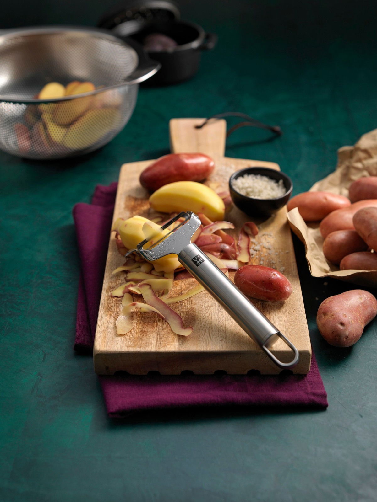 ZWILLING Pendelschäler quer ZWILLING PRO Pendelschäler quer Pro auf einem Schneidebrett mit Kartoffeln, von oben fotografiert.