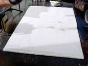 Weißer Fellteppich in einem modernen Raum, von oben betrachtet, umgeben von Möbeln und Zeitschriften.