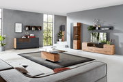 Moderne Wohnzimmerkombination mit Holz- und Glaselementen, bestehend aus Sideboard, Vitrine und TV-Board, in einem hellen Raum mit großen Fenstern, seitliche Perspektive.
