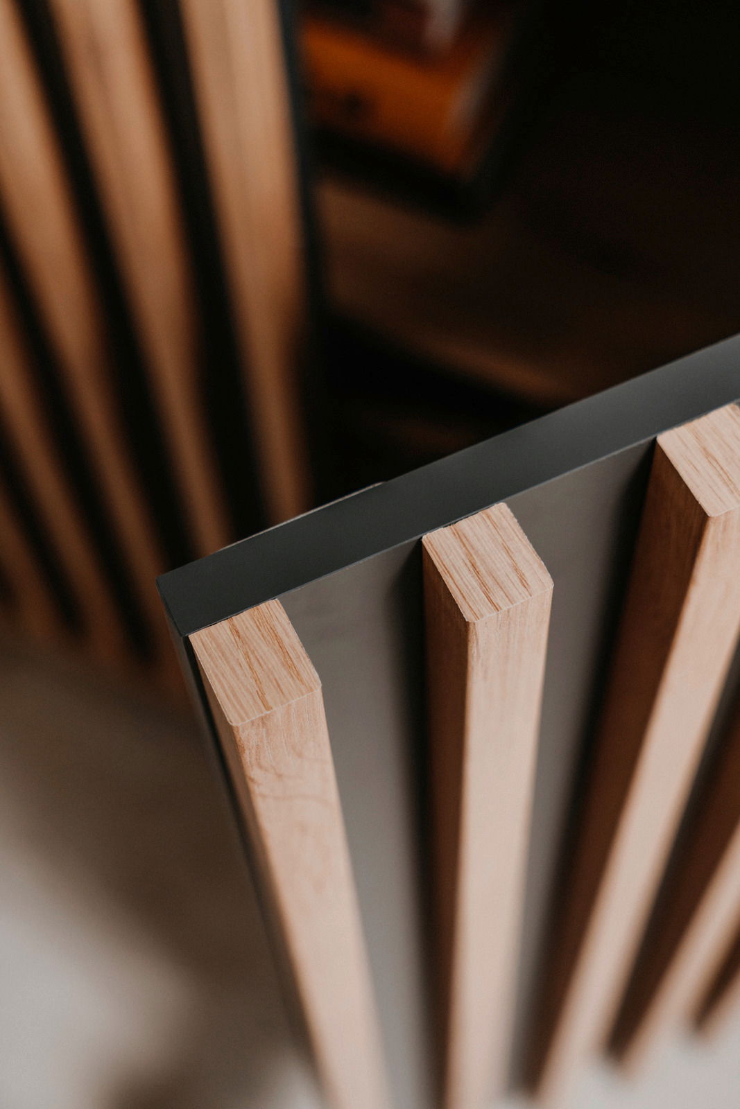 Nahaufnahme eines Sideboards mit vertikalen Holzlamellen und einer dunklen Oberfläche, aus der Vogelperspektive betrachtet.