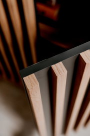 Nahaufnahme eines Sideboards mit vertikalen Holzlamellen und einer dunklen Oberfläche, aus der Vogelperspektive betrachtet.