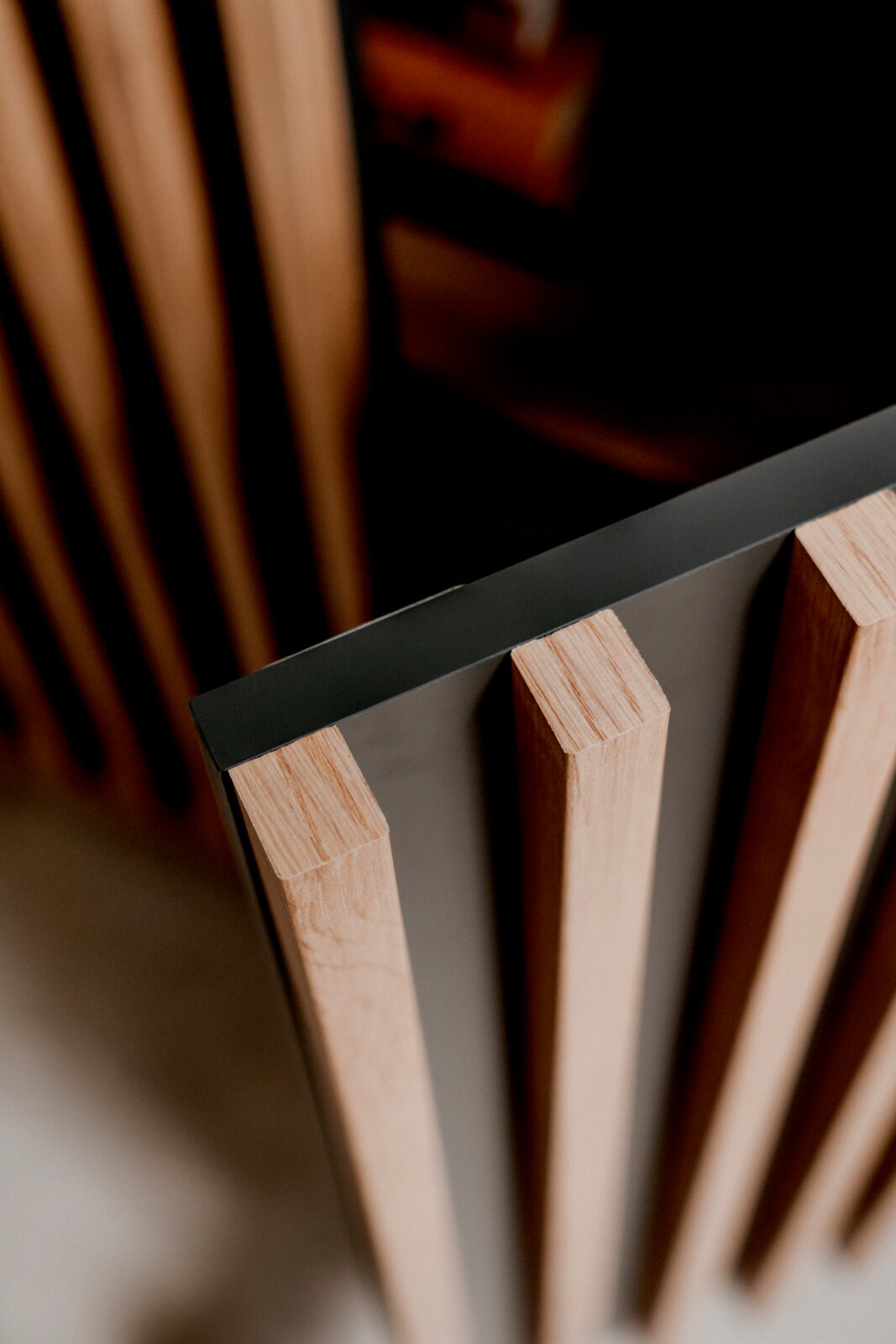 Nahaufnahme eines Sideboards mit vertikalen Holzlamellen und einer dunklen Oberfläche, aus der Vogelperspektive betrachtet.