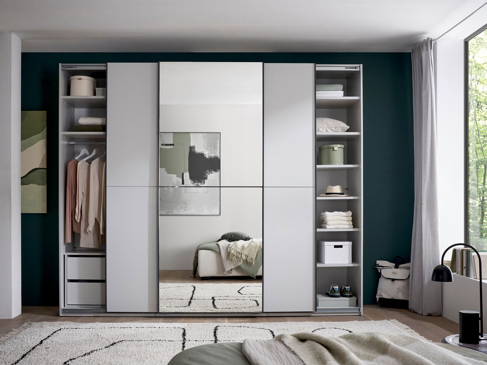 Frontansicht eines modernen Kleiderschranks in Hellgrau mit mittlerer Spiegeltür, seitlich offenen Regalfächern und Kleiderstange, im Schlafzimmer-Setting.