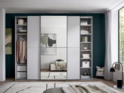 Frontansicht eines modernen Kleiderschranks in Hellgrau mit mittlerer Spiegeltür, seitlich offenen Regalfächern und Kleiderstange, im Schlafzimmer-Setting.