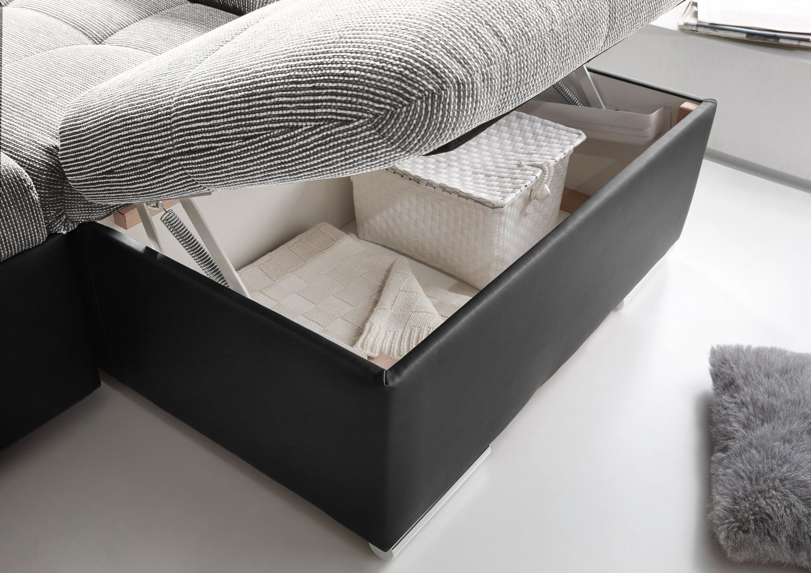 Nahaufnahme einer geöffneten Rundecke mit Stauraum, gefüllt mit einem weißen Korb und einer Decke, aus seitlicher Perspektive.