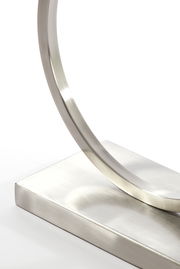 Nahaufnahme eines modernen, gebogenen Lampenfußes aus gebürstetem Metall, seitliche Perspektive.