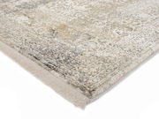 Nahaufnahme eines Designer-Teppichs mit detailliertem Muster in Grau- und Beigetönen, perspektivisch von der Ecke aufgenommen.