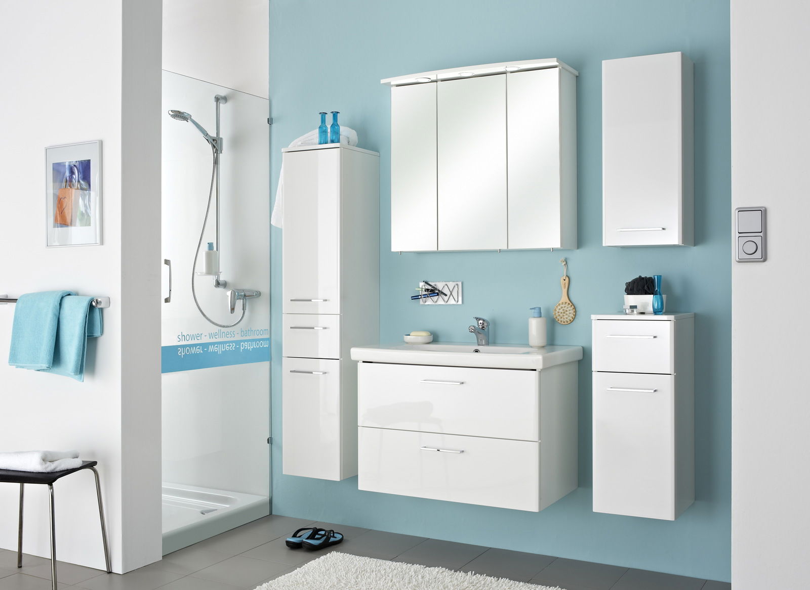 Moderner weißer Wandschrank in einem stilvollen Badezimmer, frontal betrachtet, mit blauer Wand und Dusche im Hintergrund.