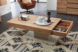 Moderner Couchtisch aus Holz mit Schublade, von schräg oben fotografiert, auf einem gemusterten Teppich stehend, dekoriert mit Tablett, Teekanne und Kerze.